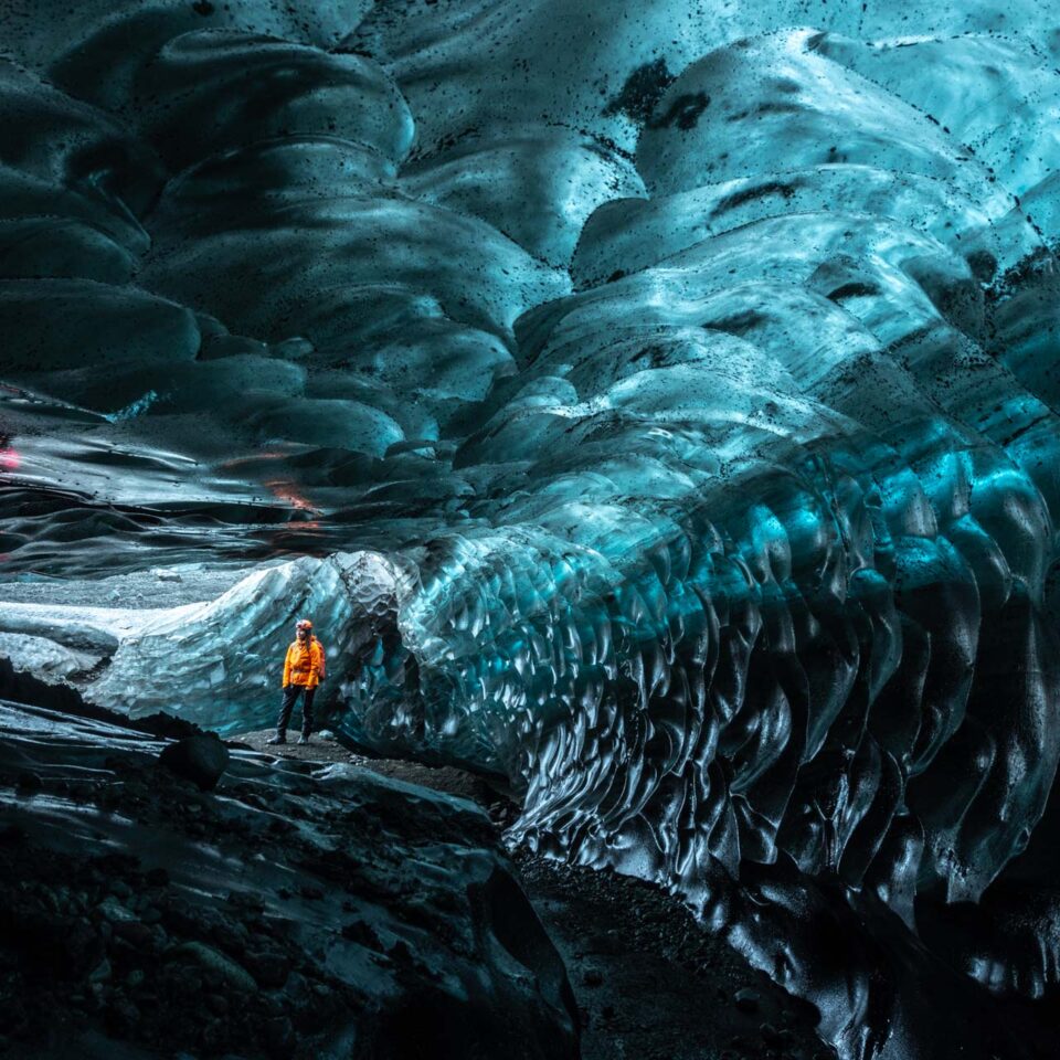 Diep onder het gletsjerijs loopt een vrouw door een ijsgrot.